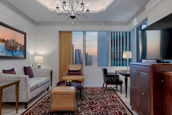 Wohnzimmer im St. Regis Abu Dhabi mit Möbeln, Teppich, Fernseher und Fenster mit Stadtblick.