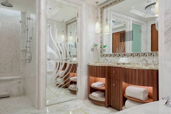 Badezimmer im St. Regis Abu Dhabi Hotel mit Marmorboden, begehbarer Dusche und Doppelwaschbecken.