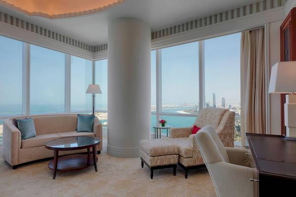 Wohnzimmer im St. Regis Abu Dhabi mit großer Fensterfront und Blick auf die Stadt.