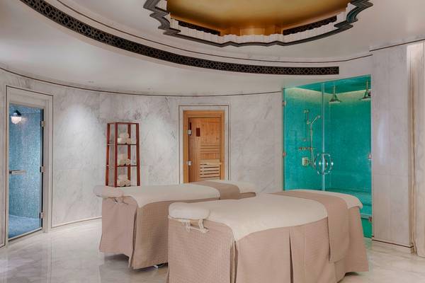 Behandlungsraum im Spa des St. Regis Abu Dhabi mit zwei Massageliegen und einer Duschkabine.