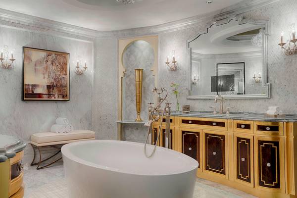 Luxuriöses Badezimmer im St. Regis Abu Dhabi mit Badewanne, goldenem Möbel und Marmorwänden.