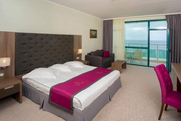 Hotelzimmer im Marina Grand Beach Hotel mit Meerblick, Bett, Schreibtisch und Sofa.