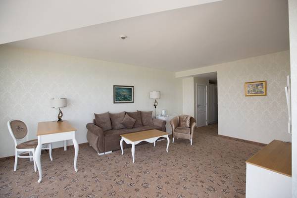 Wohnzimmer im Marina Grand Beach Hotel mit Sofa, Tisch, Stühlen und Bildern an der Wand.