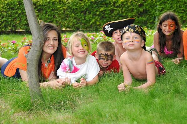 Gruppe von Kindern im Garten mit Gesichtsbemalung und Piratenkostümen, die auf dem Rasen liegen.