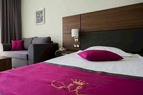 Hotelzimmer im Marina Grand Beach Hotel mit Bett, Sofa, Nachttisch und Fenster.