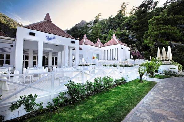 Das Hillside Beach Club Restaurant mit Außenbereich, weißen Tischen und Stühlen, umgeben von Grün.
