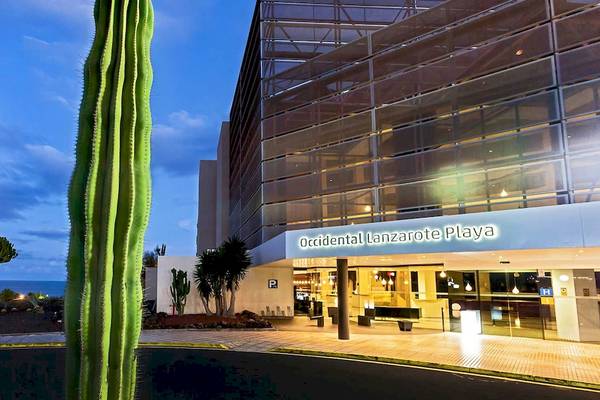 Vorderansicht des Barcelo Lanzarote Active Resort mit Kakteen vor dem Gebäude und Meer im Hintergrund