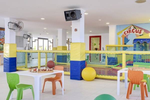 Spielplatz im Barcelo Lanzarote Active Resort mit bunten Tischen, Stühlen und einem großen gelben Ball.