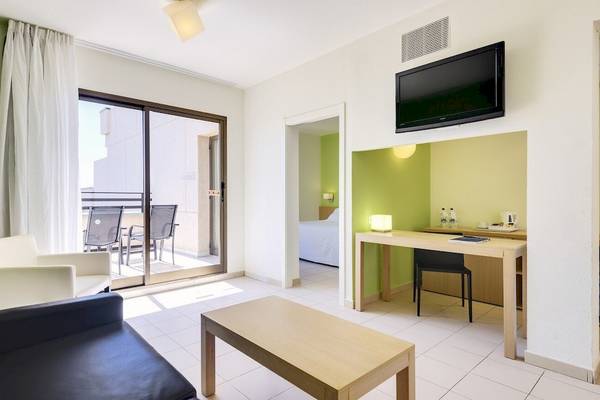 Innenansicht eines Zimmers im Barcelo Lanzarote Active Resort mit Möbeln und einem Fernseher.