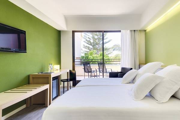 Zimmer im Barcelo Lanzarote Active Resort mit grünen Wänden, zwei Betten, Schreibtisch und Balkon mit Aussicht.