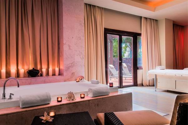 Spa-Badezimmer im Tivoli La Caleta Tenerife Resort mit Badewanne, Kerzen und Lounge-Bereich.