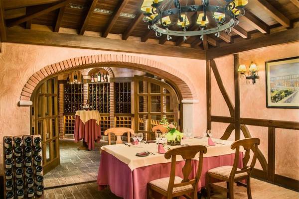 Ein elegantes Restaurant im Tivoli La Caleta Tenerife Resort mit einem Tisch, der mit Gläsern und einer Tischdecke serviert ist, in einem beleuchteten Weinkeller.