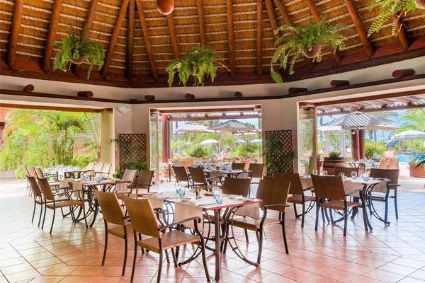 Innenbereich des Restaurants im Tivoli La Caleta Tenerife Resort mit runden Tischen und Stühlen.