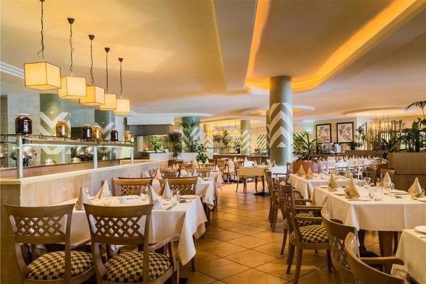 Innenansicht des Restaurants im Tivoli La Caleta Tenerife Resort mit gedeckten Tischen und Stühlen.