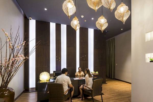 Innenansicht der Rezeption im Beyond Resort Krabi mit drei Personen, die an einem Tisch sitzen, und dekorativen Elementen wie Lampen und Pflanzen.