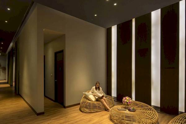 Eine Frau sitzt auf einem Korbstuhl im Hotellobby-Loungebereich des Beyond Resort Krabi.
