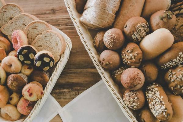 Zwei Körbe mit verschiedenen Gebäckstücken und Broten auf einem braunen Tisch