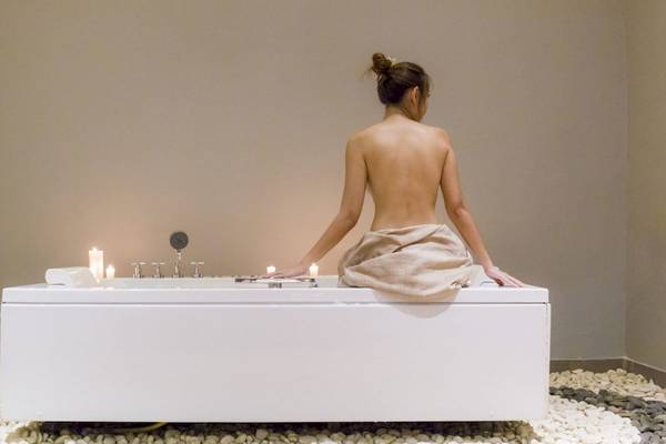 Frau sitzt nackt auf einer weißen Badewanne mit Kerzen im Beyond Resort Krabi.