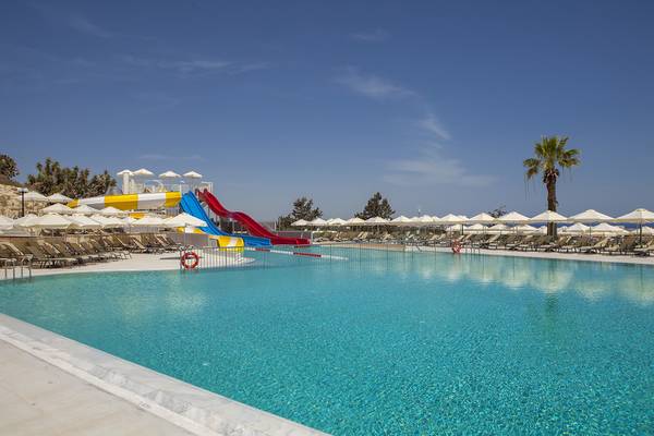Außenpool mit Wasserrutschen und Liegen im Louis St. Elias Resort & Waterpark