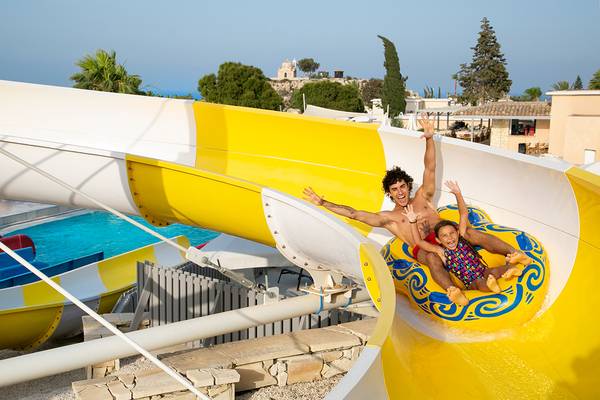 Mann und Kind rutschen auf einer gelben Wasserrutsche im Louis St. Elias Resort & Waterpark