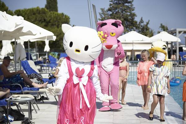 Mascots von Hello Kitty und Pink Panther gehen am Pool des Louis St. Elias Resorts entlang.