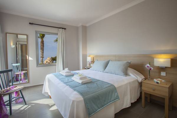 Schlafzimmer im Louis St. Elias Resort mit Bett, Nachttisch, Spiegel und Fenster