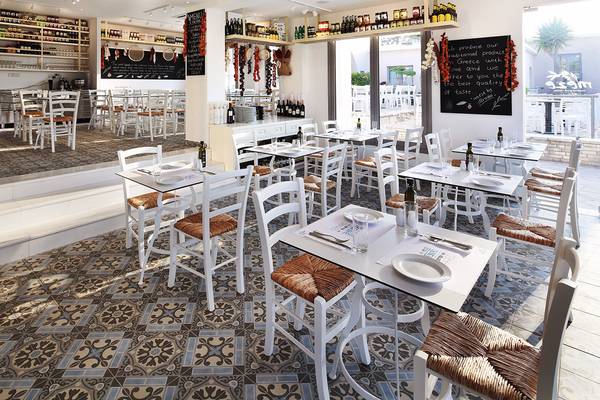 Innenansicht des Restaurants im Louis St. Elias Resort & Waterpark mit weißen Tischen und Stühlen, gefliesten Böden und einer Tafel mit Speisen.