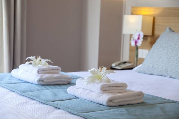 Bett im Louis St. Elias Resort mit weißen Handtüchern und Bettlaken