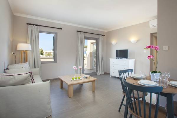 Wohnzimmer im Louis St. Elias Resort mit Sofa, Tisch, Fernseher und Esstisch