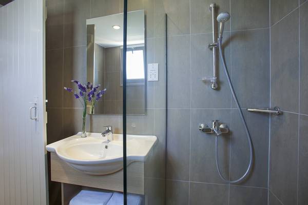 Ein Badezimmer mit einer Duschkabine, Waschbecken und einem Spiegel, Louis St. Elias Resort & Waterpark.