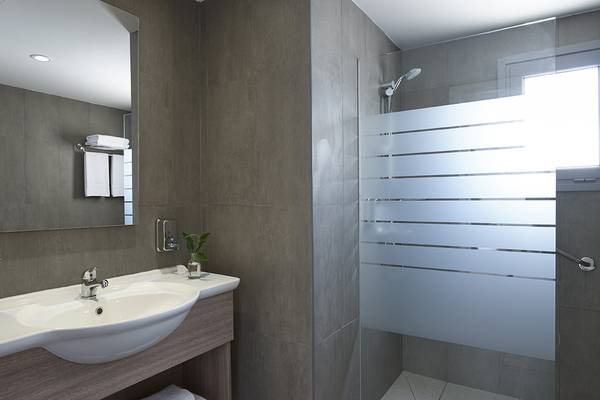 Badezimmer im Louis St. Elias Resort & Waterpark mit Waschbecken, Spiegel und Dusche.