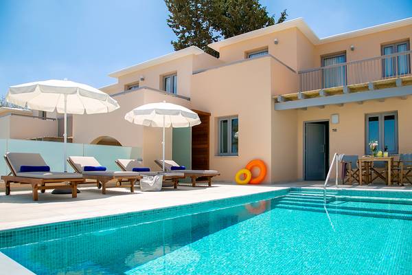 Ein Swimmingpool und Lounge-Sessel vor einem Hotelgebäude.