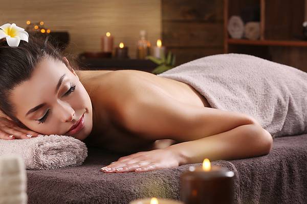 Eine Frau genießt eine Massagebehandlung im Ellaidhoo Maldives Spa mit Kerzen und Blütenblättern.