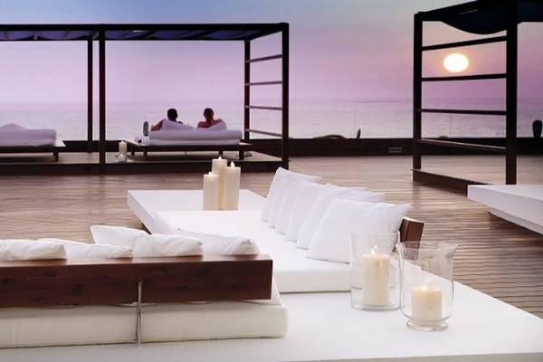 Loungebereich des H10 Gran Tinerfe Hotels mit Blick auf den Ozean und zwei Personen, die sich entspannen.