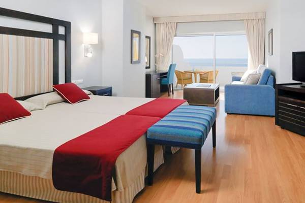 Hotelzimmer im H10 Gran Tinerfe mit zwei Betten, einem Fernseher, einem Schreibtisch und einem Balkon.