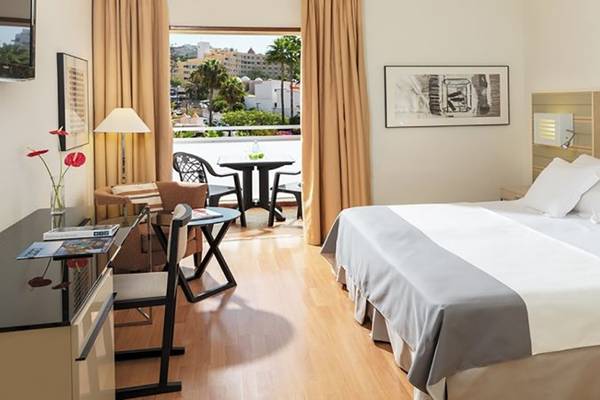 H10 Gran Tinerfe Hotelzimmer mit Balkon, Bett, Tisch und Stühlen.