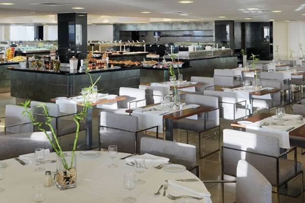 Das Restaurant des H10 Gran Tinerfe Hotels mit vielen gedeckten Tischen und einer Theke mit verschiedenen Speisen.