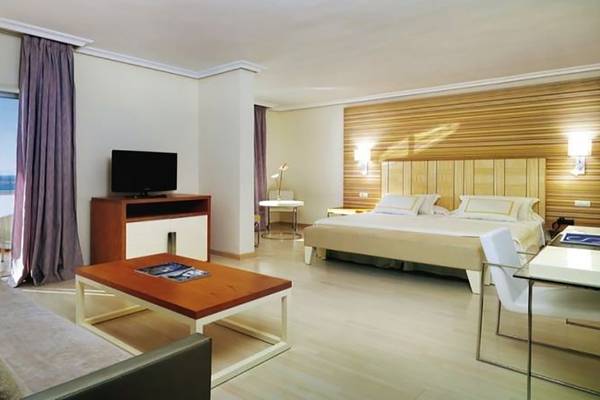 Suite-Zimmer im H10 Gran Tinerfe Hotel mit Meerblick, Bett, Fernseher, Tisch und Sofa.