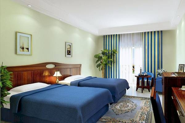 Doppelzimmer im Stella Gardens Resort & Spa Makadi Bay mit zwei Betten, Schreibtisch, Fernseher und Pflanzen.