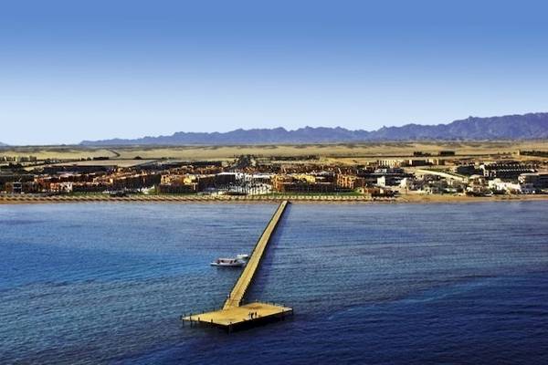 Luftaufnahme des Stella Gardens Resort & Spa Makadi Bay mit einer langen Brücke und einem Boot im Wasser.