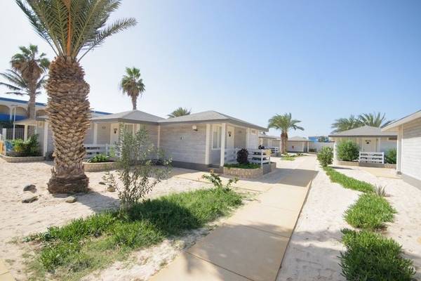 Reihe von weißen Bungalows am Strand, umgeben von Palmen und Pflanzen, Oasis Belorizonte Hotel.