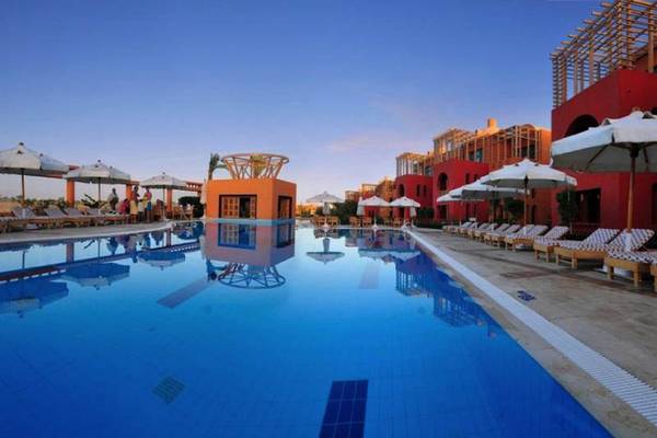 Außenpool des Steigenberger Golf Resort El Gouna mit roten Gebäuden und Sonnenliegen