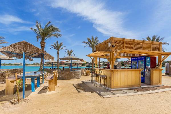Strandimbiss am Steigenberger Golf Resort El Gouna mit Holzbar, Tischen und Stühlen im Freien.