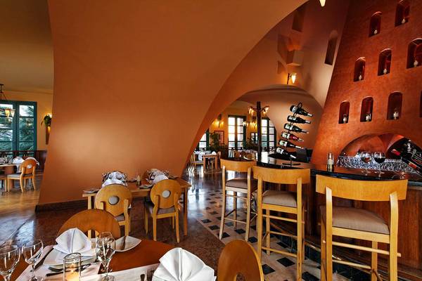 Innenbereich des Restaurants im Steigenberger Golf Resort El Gouna mit runden Tischen, Stühlen und einer Theke.