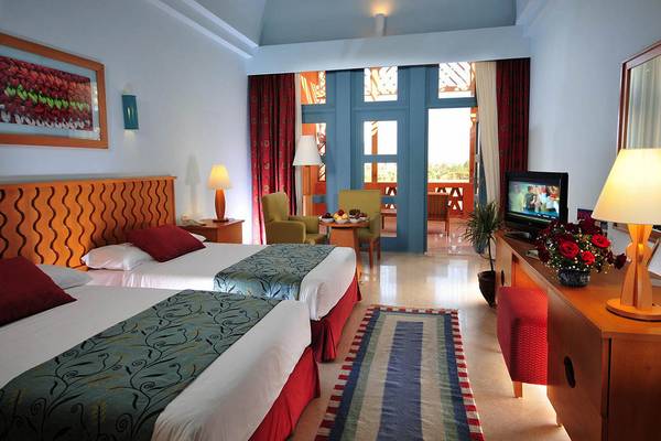 Doppelzimmer im Steigenberger Golf Resort El Gouna mit zwei Betten, Fernseher, Tisch und Stühlen.