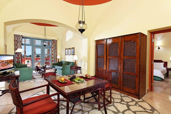 Wohnzimmer des Steigenberger Golf Resort El Gouna mit Esstisch, grünem Sofa und Fernseher.