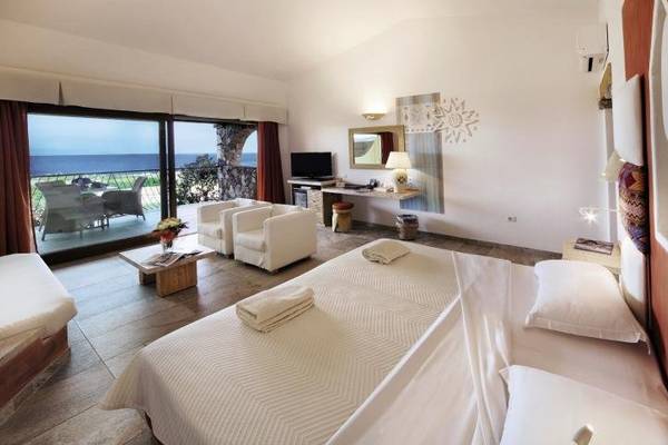 Schlafzimmer im Resort Valle Dell'Erica Thalasso & Spa mit Meerblick, inklusive zwei weißer Sessel und Fernseher.