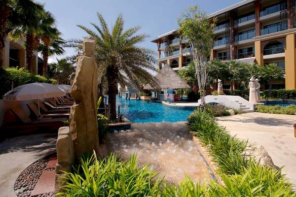 Außenbereich des Rawai Palm Beach Resorts mit Swimmingpool, Sonnenliegen und Palmen