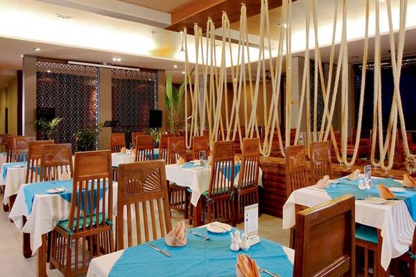 Innenbereich eines Restaurants im Rawai Palm Beach Resort mit blauen Tischdecken und hölzernen Stühlen.
