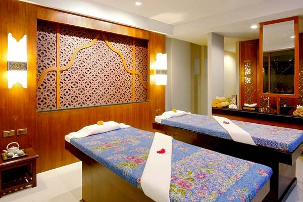 Massageraum im Rawai Palm Beach Resort mit zwei Massagebetten und dekorativen Elementen.